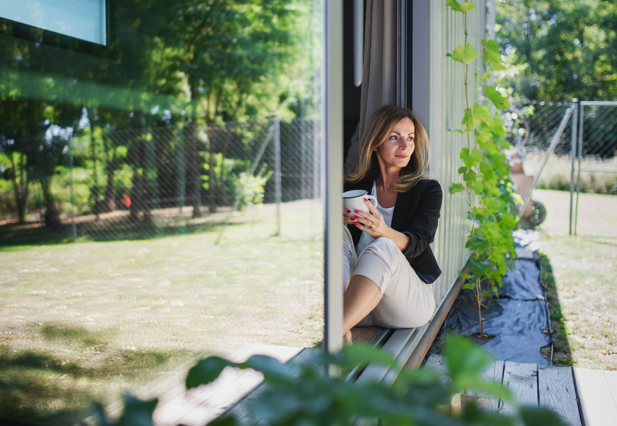 A woman sitting on her detached adu office doorstep - contact RiseCon backyard office contractors in California to build yours today.